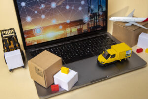 Laptop showing connected logistics tracking with delivery vehicles, parcels and air freight representing automated delivery updates